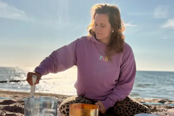 Eine Frau sitzt auf einer Decke am Strand.