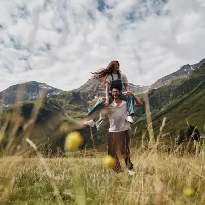 Berglandschaft Sommer Bad Gastein Ein Mann trägt eine Frau auf den Schultern und im Hintergrund sind Berge zu sehen.