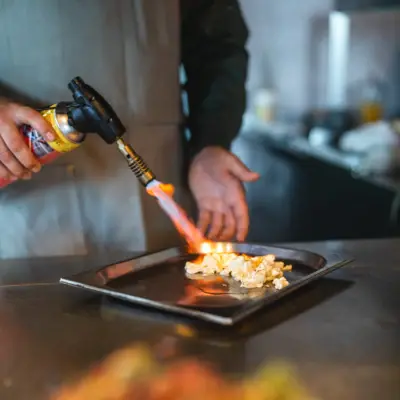 Flambieren Ein Koch flambiert eine Speise auf einem Tabelett.