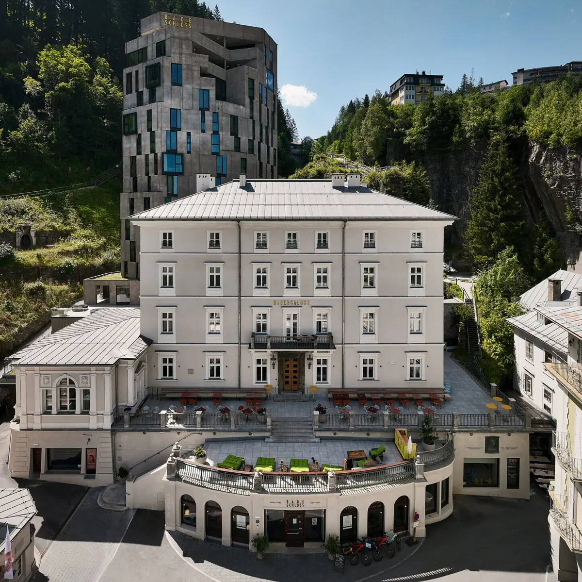 Ein Gebäude mit einem großen Balkon und ein großes Gebäude mit Bäumen im Hintergrund.