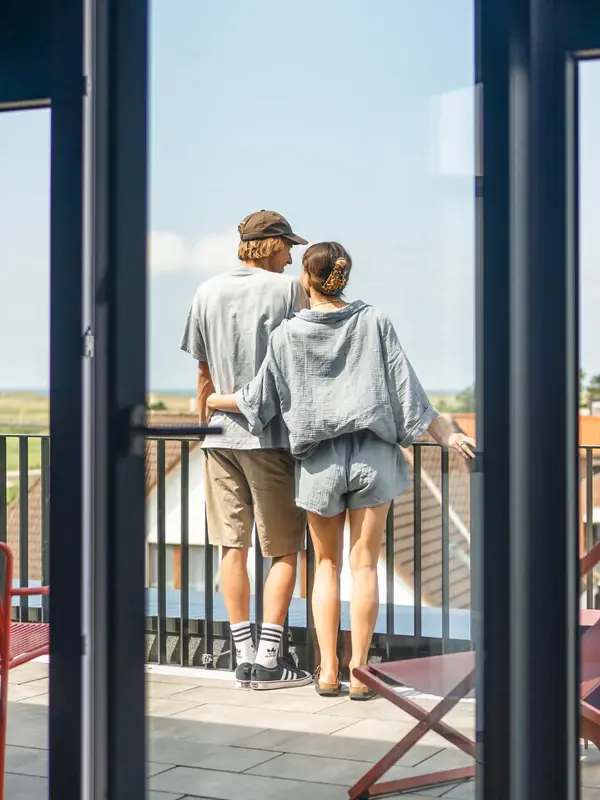 Ein Mann und eine Frau stehen auf einem Balkon und genießen die Aussicht.