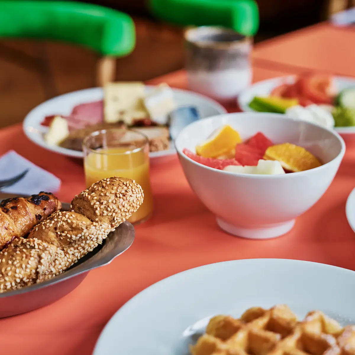 Ein Frühstückstisch mit Speisen wie Obst, Brot, Eiern und Orangensaft.