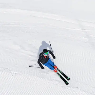 Skifahren Ein Skifahrer mit einer blauen Hose fährt auf einer Piste.