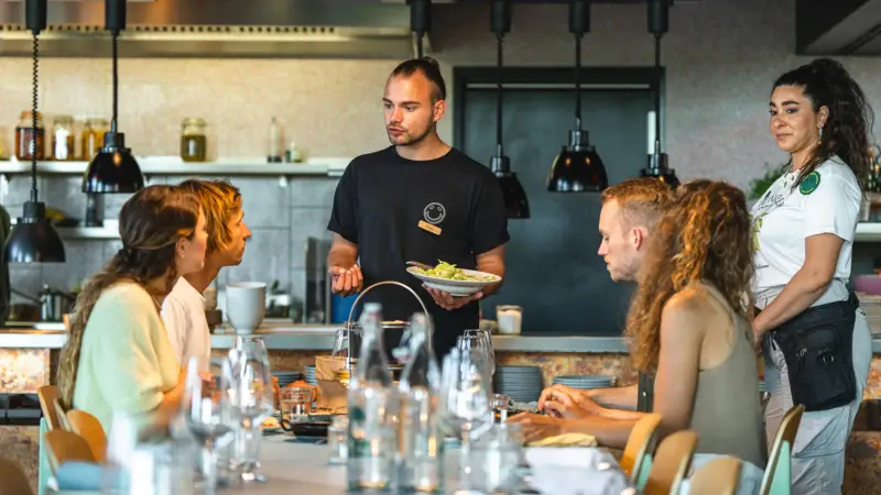 Service Auntie Clara Ein Mann bedient eine Gruppe von Menschen in einem Restaurant.