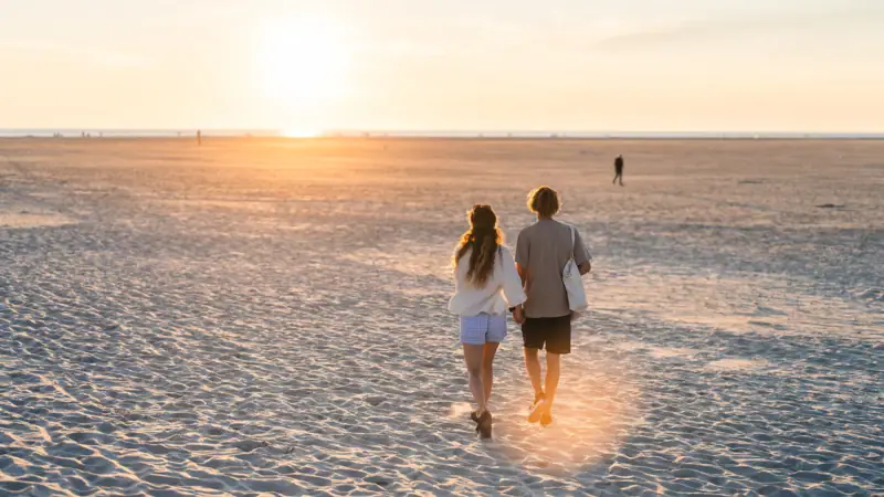 Ein Paar spaziert am Strand entlang.