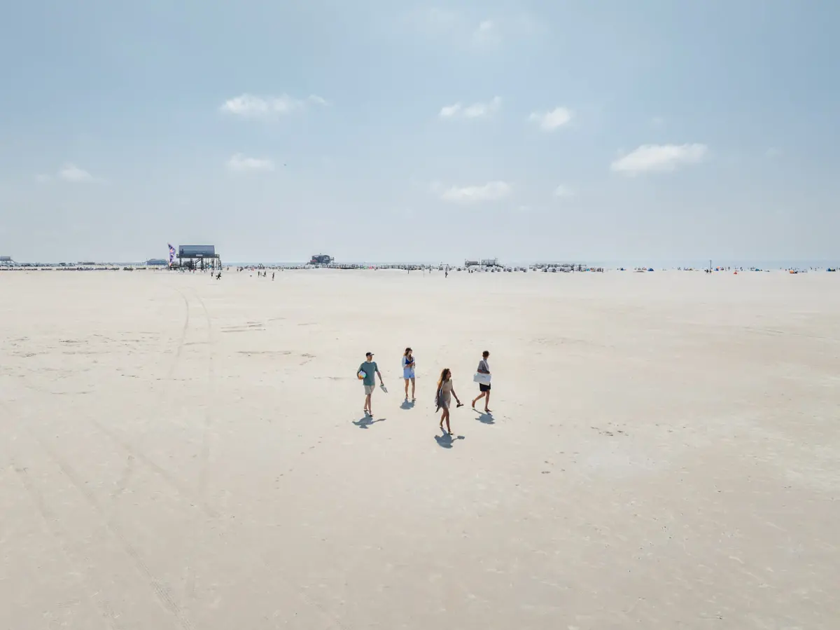 Eine Gruppe von Menschen spaziert am Strand.