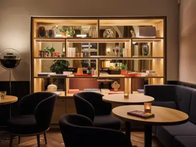 Stilvoller Lounge-Bereich im Urban Nature Hotel Bad Gastein mit Regal, Vasen, Kerzenlicht und gemütlichen Sesseln