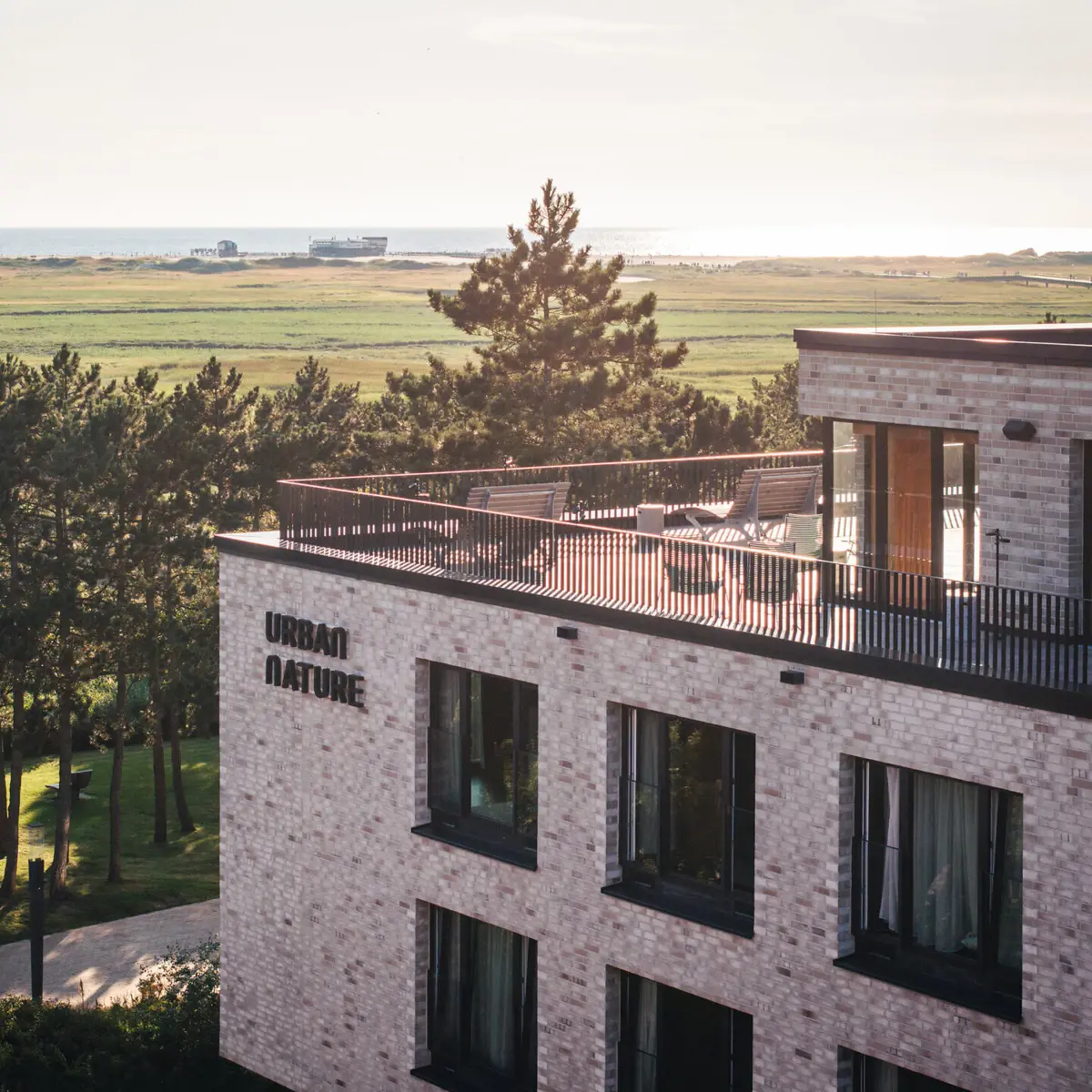 Das Urban Nature Hotel in St. Peter-Ording mit einer großen Dachterrasse von außen fotografiert.