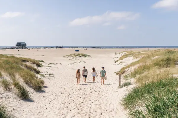 Nordsee St. Peter Ording Eine Gruppe von Menschen, die am Strand spazieren geht.
