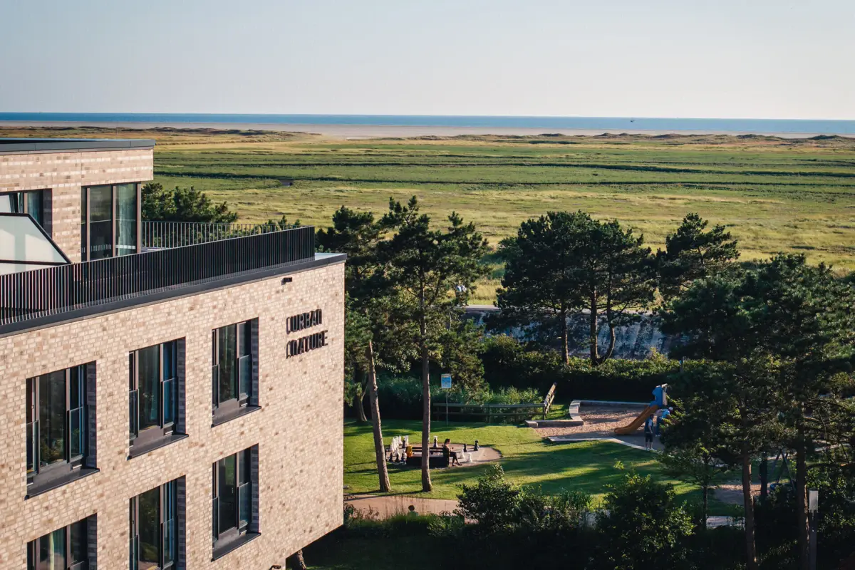 Das Urban Nature Hotel in St. Peter-Ording von außen mit Blick auf die Salzwiesen und das Meer..