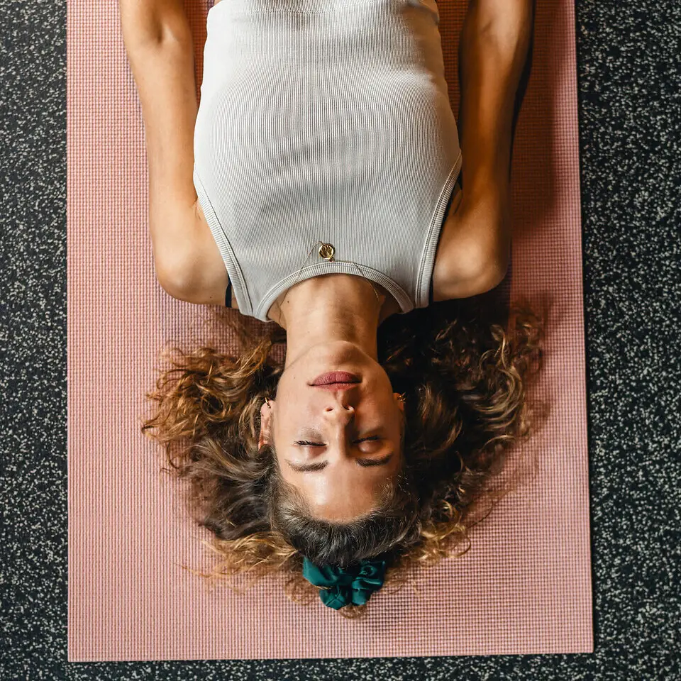 Eine Frau liegt auf einer Yogamatte und hat die Augen geschlossen.