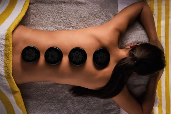 Frau bei Hot-Stone-Massage mit schwarzen Lavasteinen auf dem Rücken