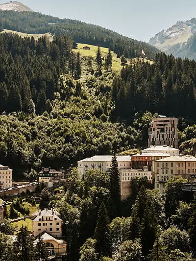 Historische Gebäude und moderner Hotelturm eingebettet in die grüne Berglandschaft von Bad Gastein im Sommer