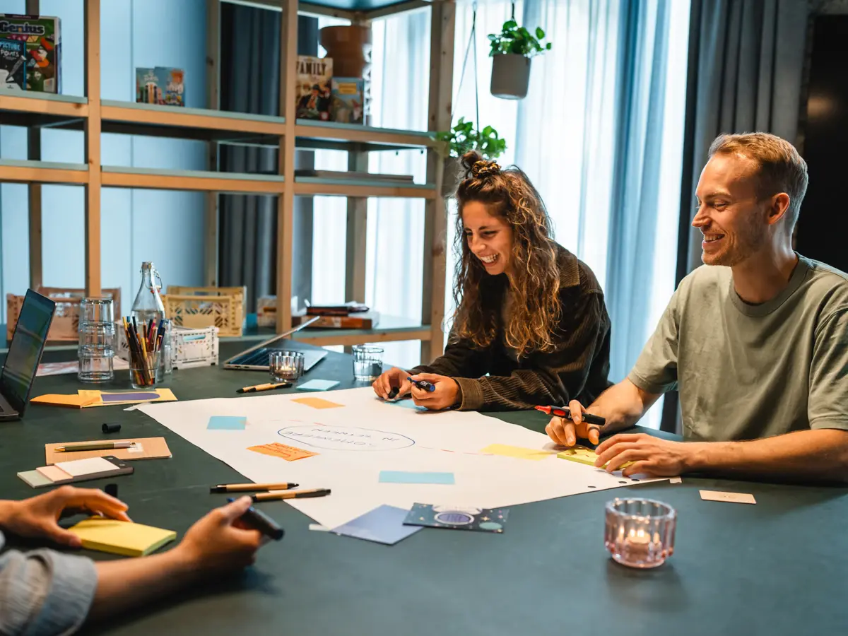 Workshop St. Peter-Ording Mehrere Menschen sitzen an einem Tisch und arbeiten an einem Plakat.