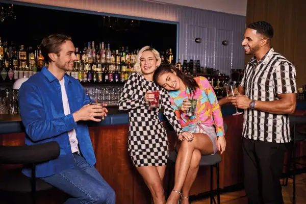 Drei junge Erwachsene genießen bunte Cocktails an einer stilvollen Hotelbar