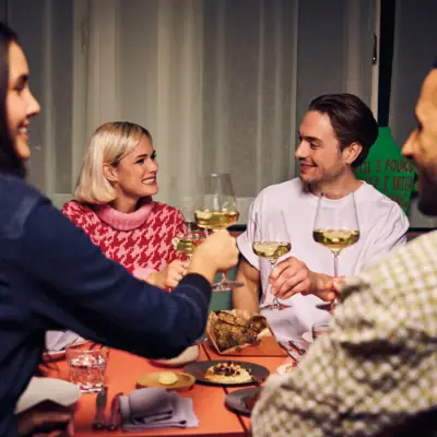 Dinner Eine Gruppe von Menschen sitzt um einen Tisch mit Weingläsern.
