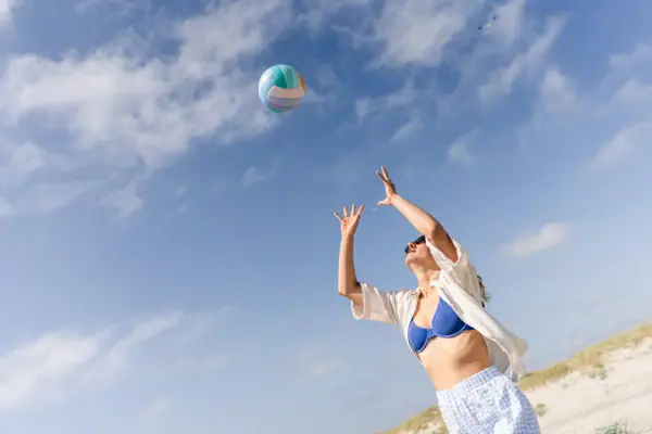 Eine Frau spielt mit einem Beachvolleyball am Strand von St. Peter-Ording.