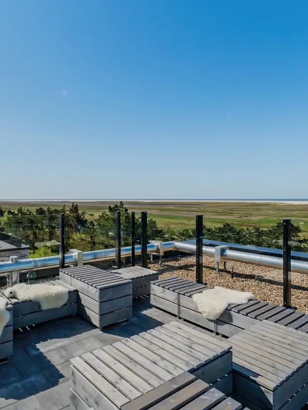 Die Rooftopbar Scraper's Club im Urban Nature Hotel St. Peter Ording mit Bänken und Tischen aus Holz.