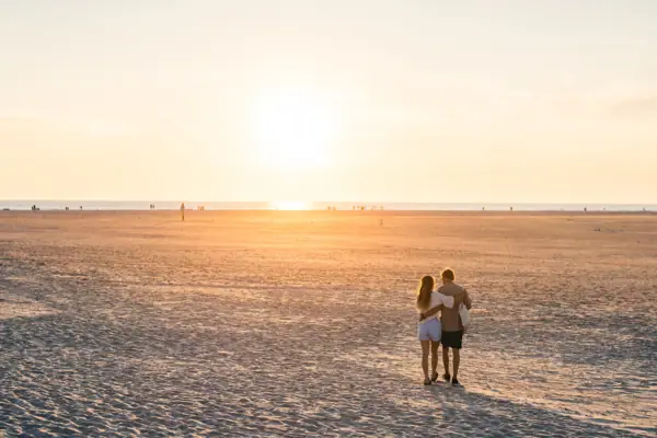 Zwei Menschen am Strandabschnitt Ording Nord in St. Peter-Ording bei Sonnenuntergang.