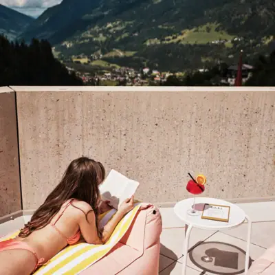 Eine Frau in einem Kleid liest ein Buch auf einem Deck.