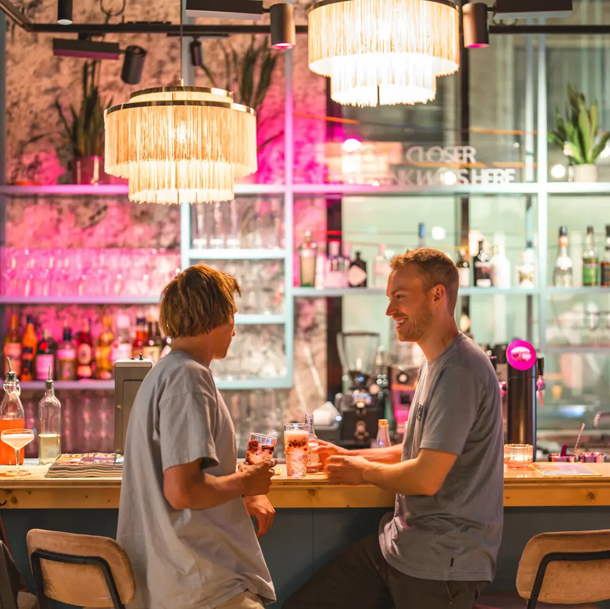 Zwei Männer stehen an der Bar vom Drifters Hang Out und haben Drinks in der Hand.