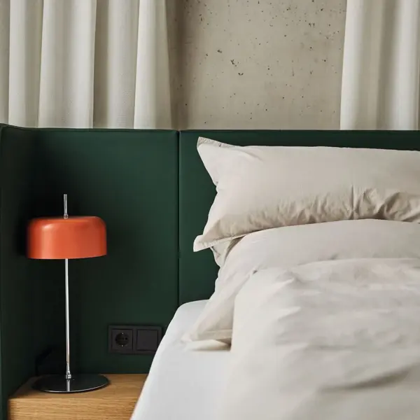 Ein Bett mit einer orangenen Nachttischlampe daneben. 