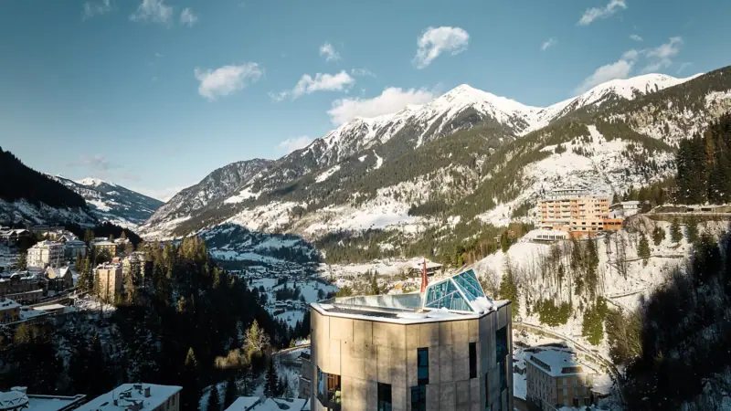 Gasteiner Tal Ein Gebäude in den Bergen mit verschneiten Gipfeln im Hintergrund.
