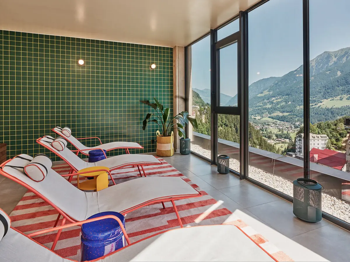 Spa-Bereich Urban Nature Badeschloss Bad gastein Mehere Liegen stehen vor einem Fenster mit Blick auf eine Berglandschaft.