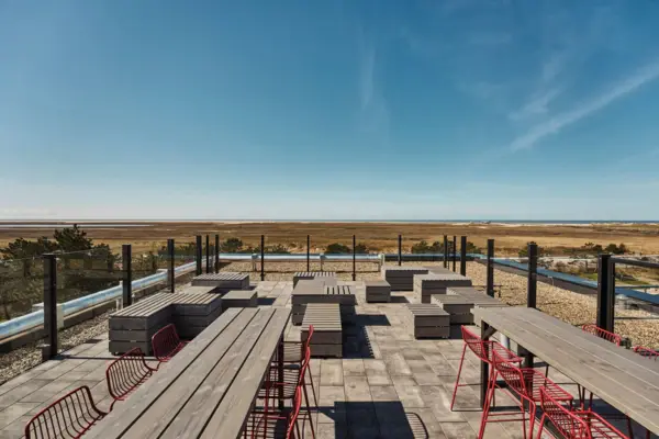 Eine Terrasse mit einigen Tischen und Bänken mit Blick auf die Salzwiesen und die Nordsee in St. Peter-Ording.
