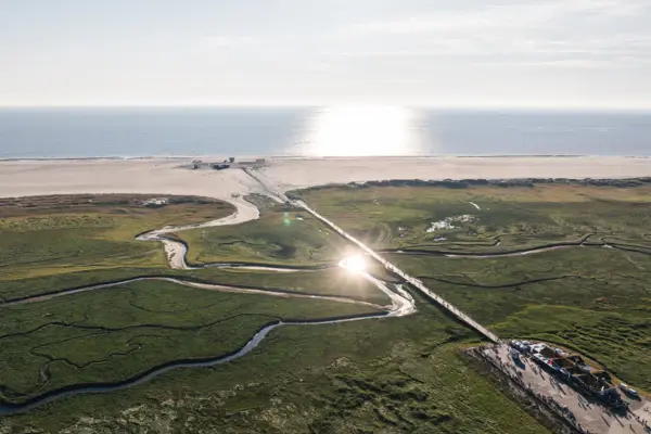 Ein Weg, die zu einem Strand führt, mit Himmel und Wasser im Hintergrund.