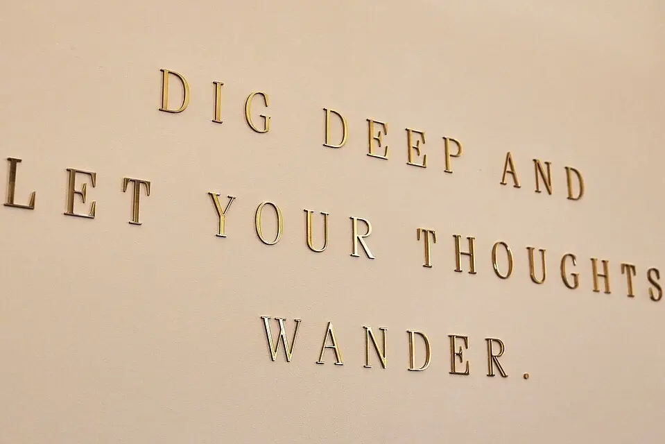 Wandzitat in goldener Schrift: „Dig deep and let your thoughts wander“ – inspirierender Spruch in modernem Interieur
