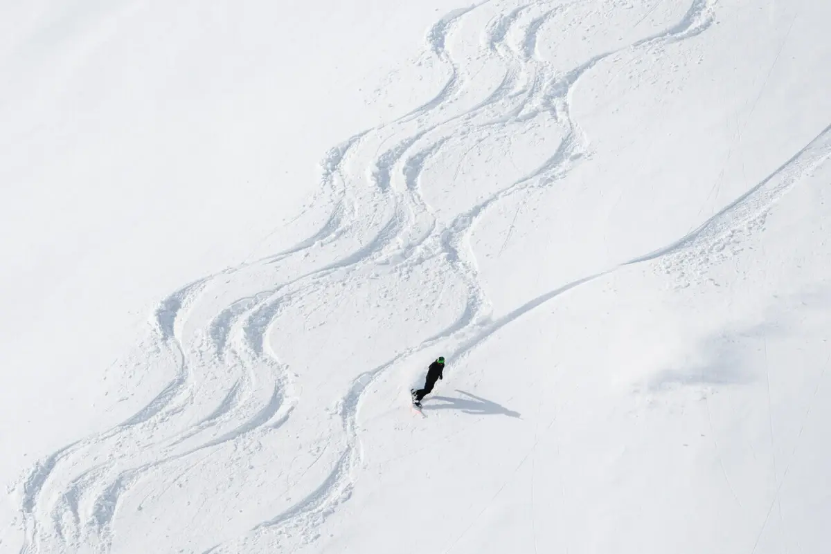Ein Snowboarder fährt durch Tiefschnee einen Berg hinunter.