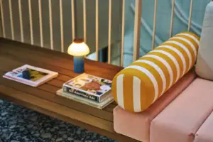 Ein Tisch mit einer Lampe und einem gelb-weiß gestreiften Kissen.