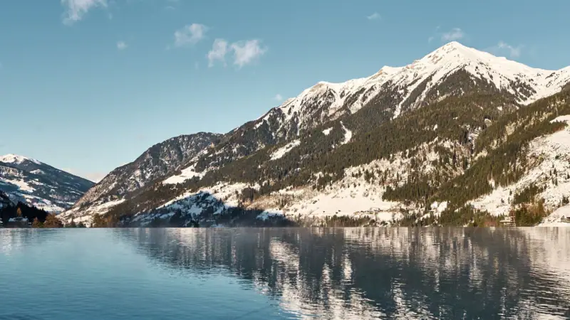 Ein Gewässer mit schneebedeckten Bergen und blauem Himmel.