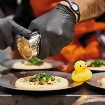 Mehrere Teller Hummus werden von einem Koch angerichtet.