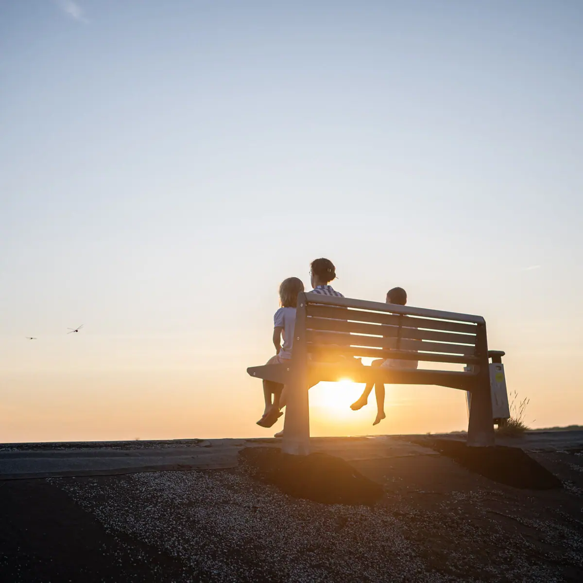 Eine Gruppe von Menschen sitzt auf einer Bank im Freien.