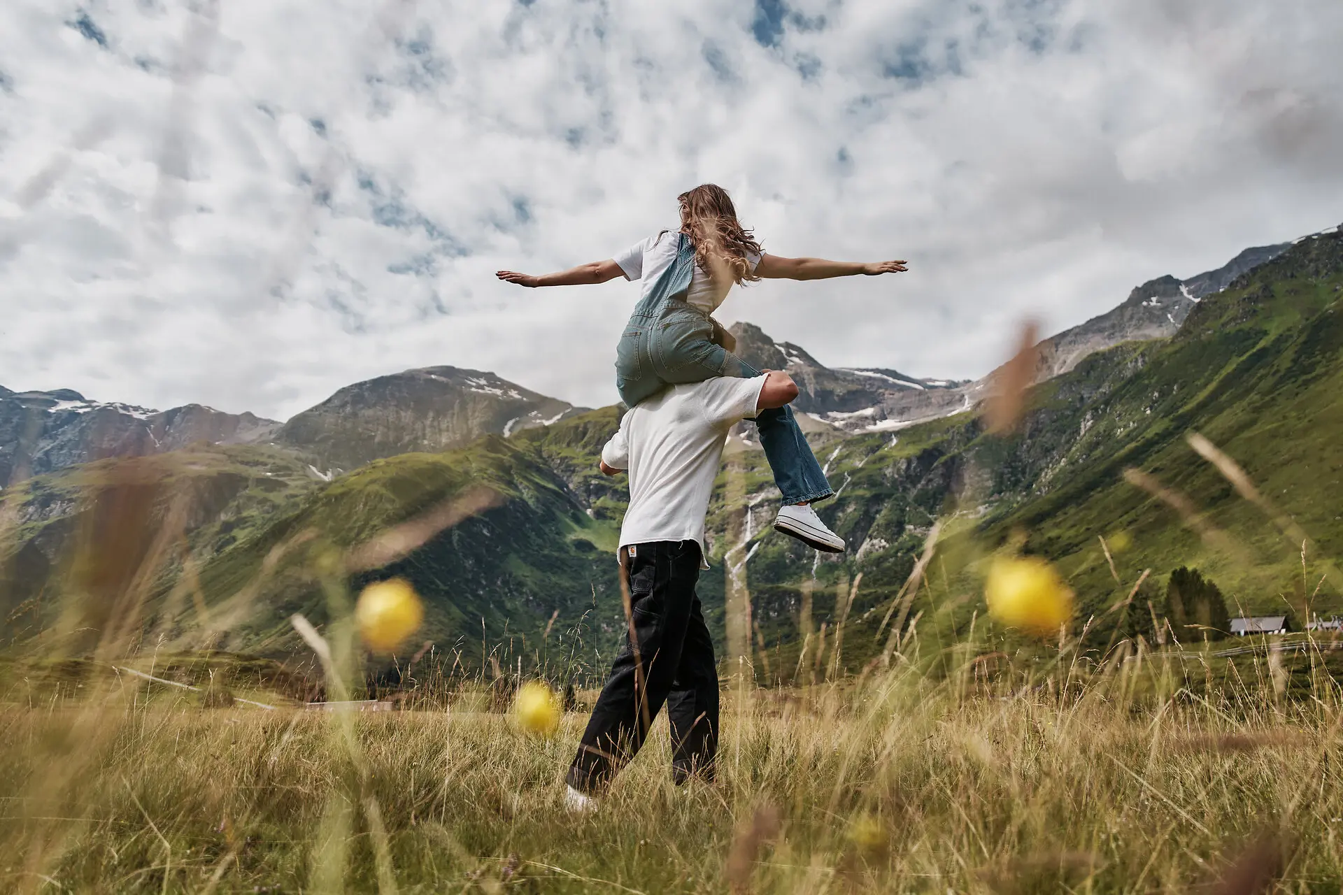 Ein mann trägt eine Frau in einer Berglandschaft auf den Schultern.