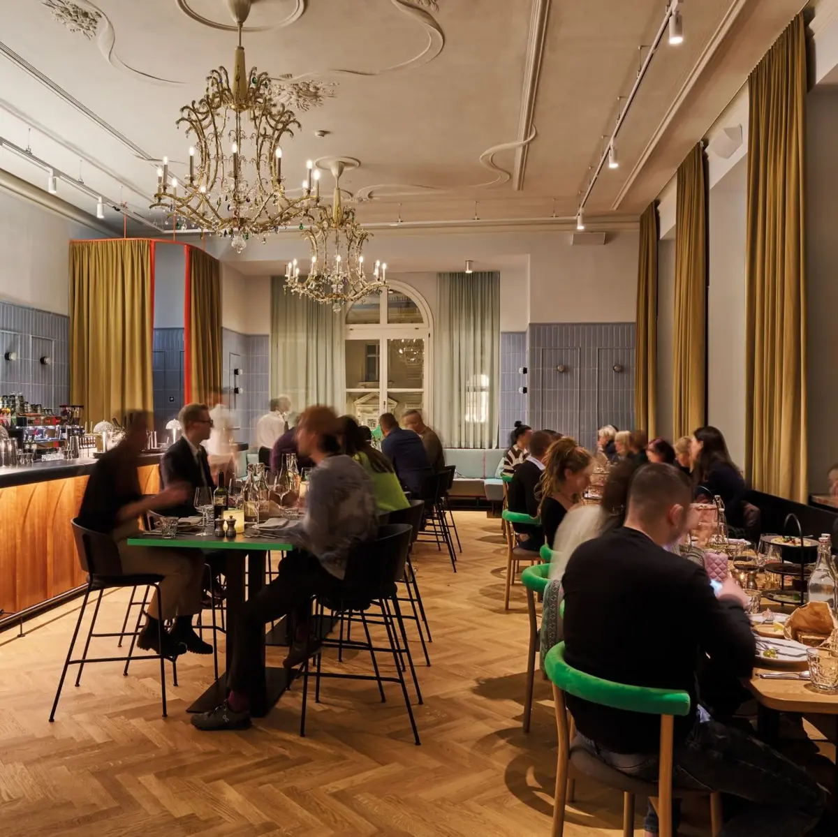 Stimmungsvoller Abend im eleganten Restaurant mit Kronleuchtern, Barbereich und lebhafter Atmosphäre