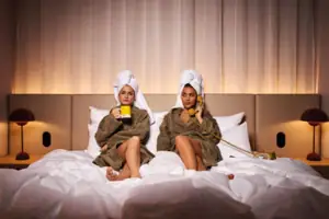 Zwei Frauen in Bademänteln auf einem Bett.
