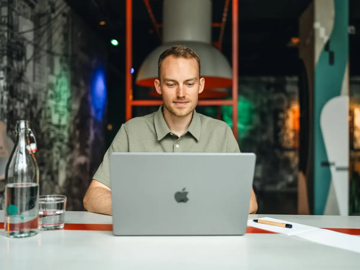 Ein Mann sitzt an einem Tisch und benutzt einen Laptop.