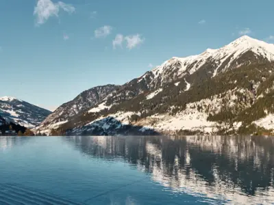 Pool Winter Bad Gastein Hinter einer Wasseroberfläche ist ein Schneebedeckter Berg zu sehen.