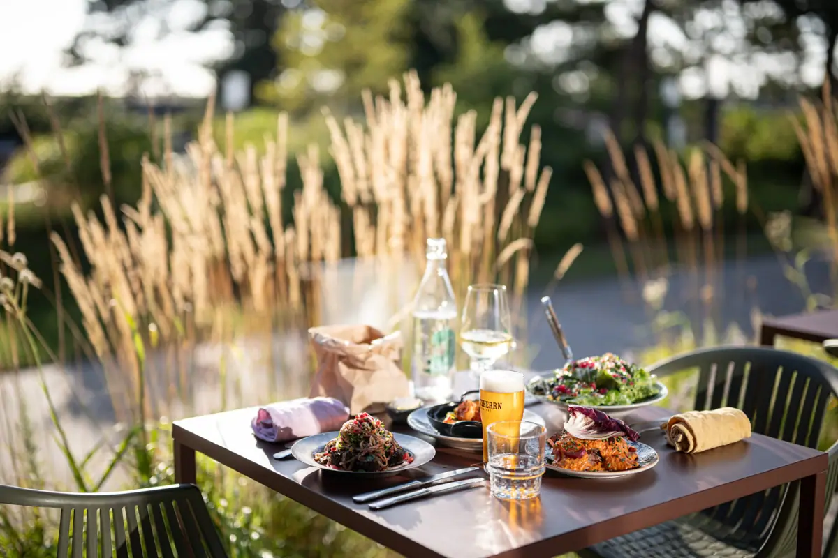 Ein Tisch auf der Terrasse vom im Auntie Clara Restaurant in St. Peter-Ording mit Speisen und Getränken darauf.