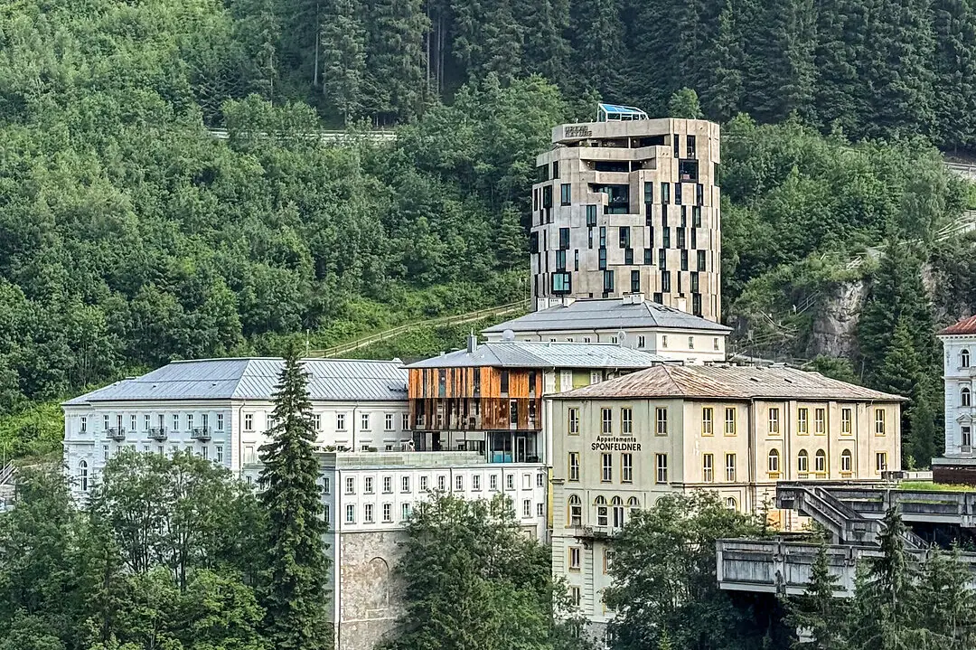 Ein Gebäude in der Nähe eines Waldes mit Bäumen und Bergen im Hintergrund.