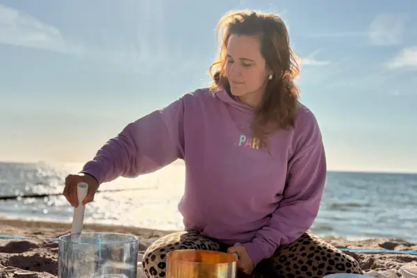 Eine Frau sitzt auf einer Decke am Strand.