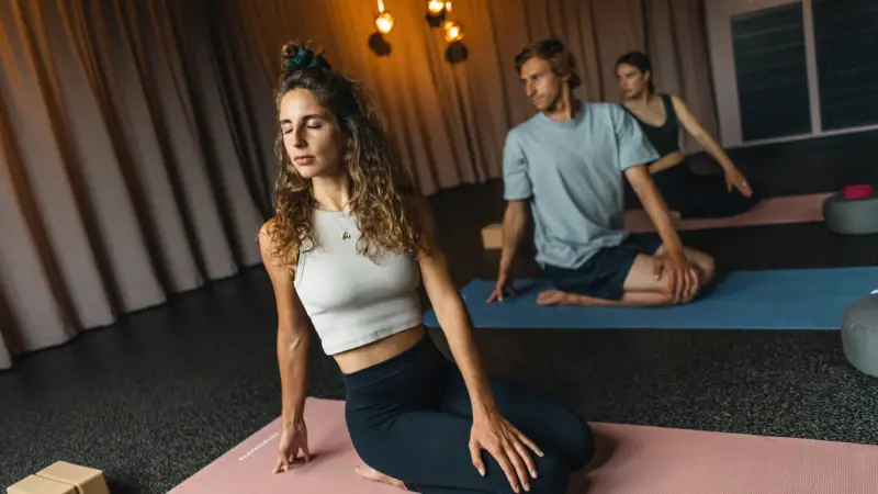Drei Personen entspannen beim Yoga machen auf Matten und halten die Augen geschlossen.