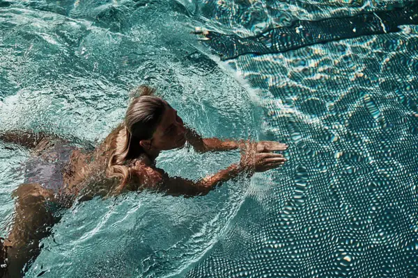 Frau schwimmt im türkisblauen Pool