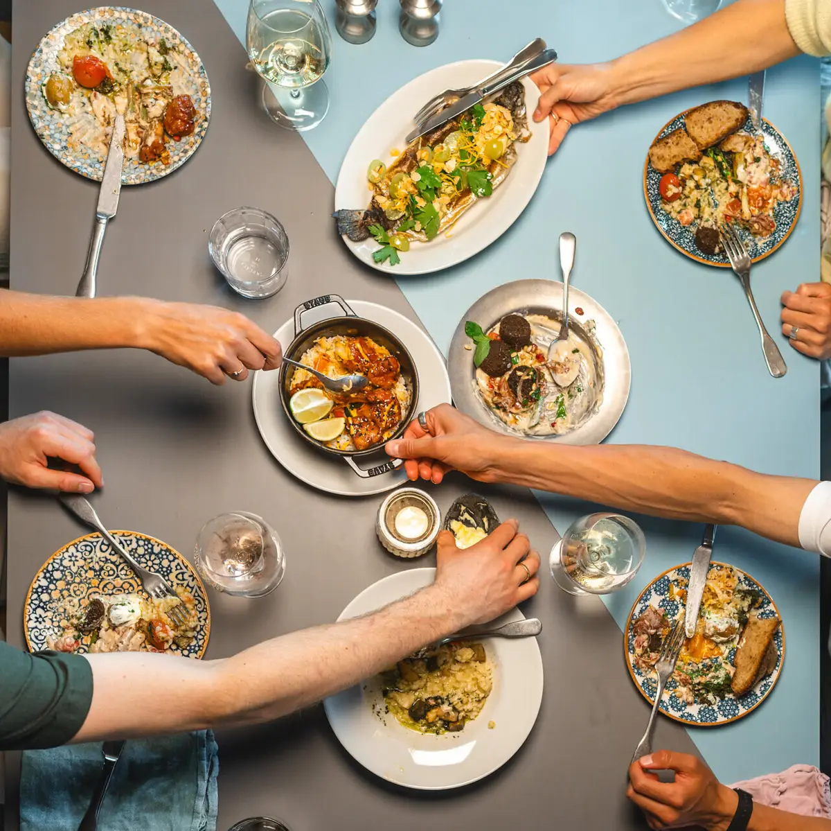 Auf einem Tisch im Auntie Clara Restaurant St.Peter-Ording stehen viele Teller und Vorspeisen in der Mitte, die sich eine Gruppe von Personen teilt.