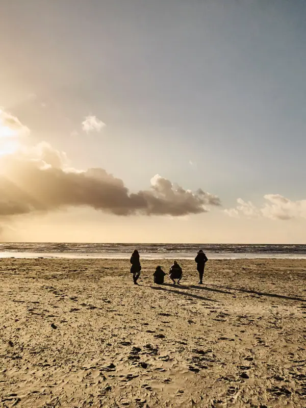 Menschen gehen am Strand entlang.