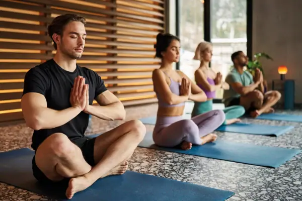 Yoga im Urban Nature Bad Gastein Eine Gruppe von Menschen sitzt auf Yogamatten mit zusammengelegten Händen.