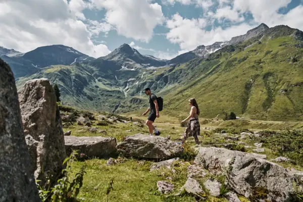 Bad Gastein Ein Mann und eine Frau wandern auf einem felsigen Hang mit Bergen im Hintergrund.